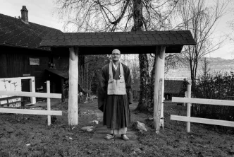 Mönch in traditioneller Robe vor Tempel