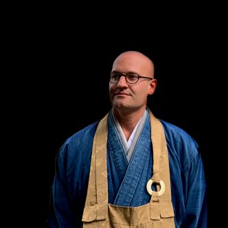 Person in traditioneller blauer Kleidung mit goldenen Details.